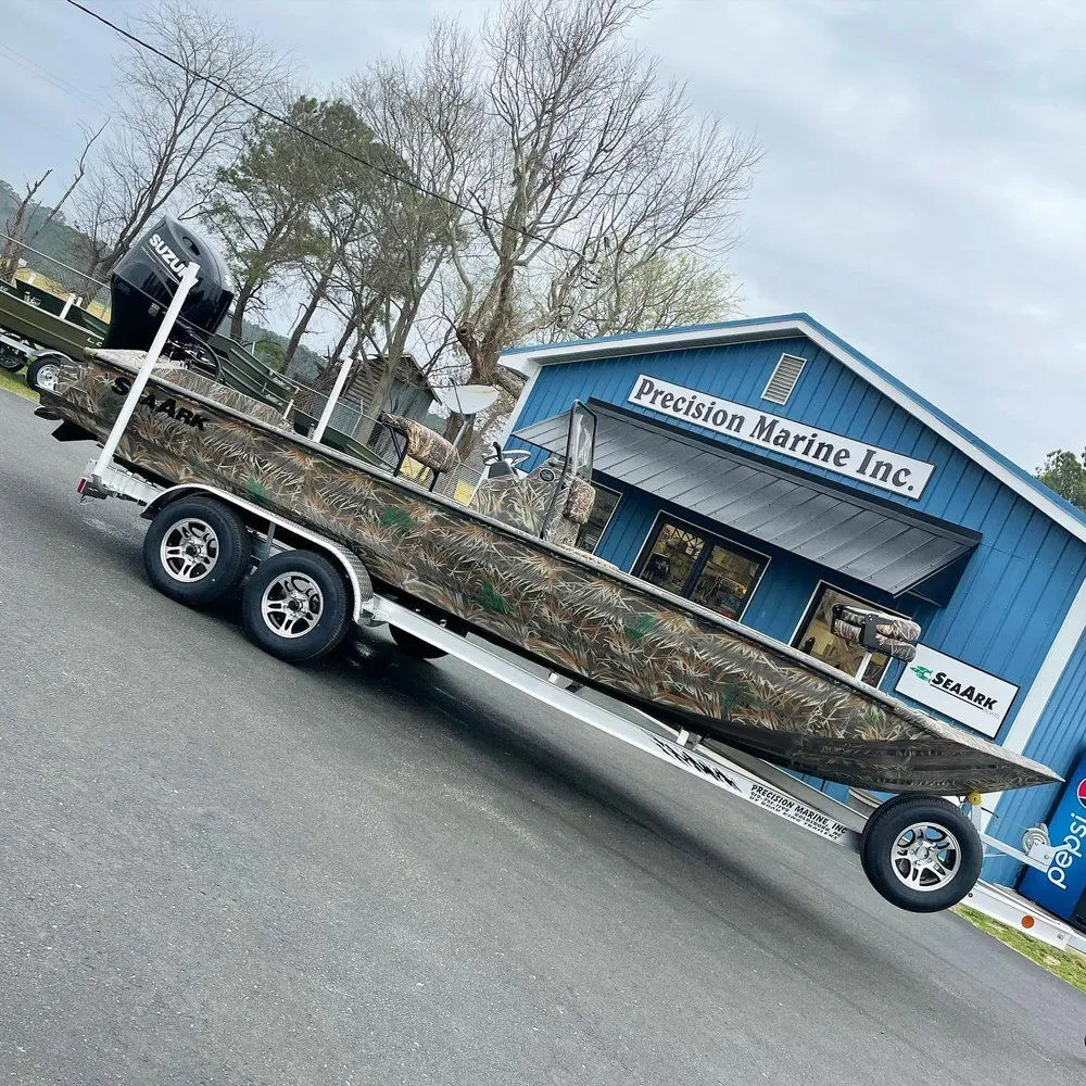 Camouflaged fishing boat on a trailer outside a blue marine business building