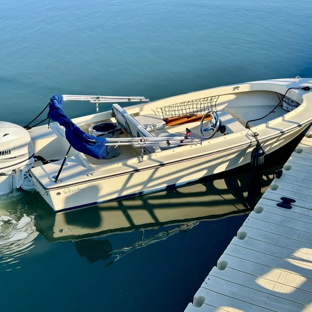 Small white motorboat tied to a dock on calm blue water