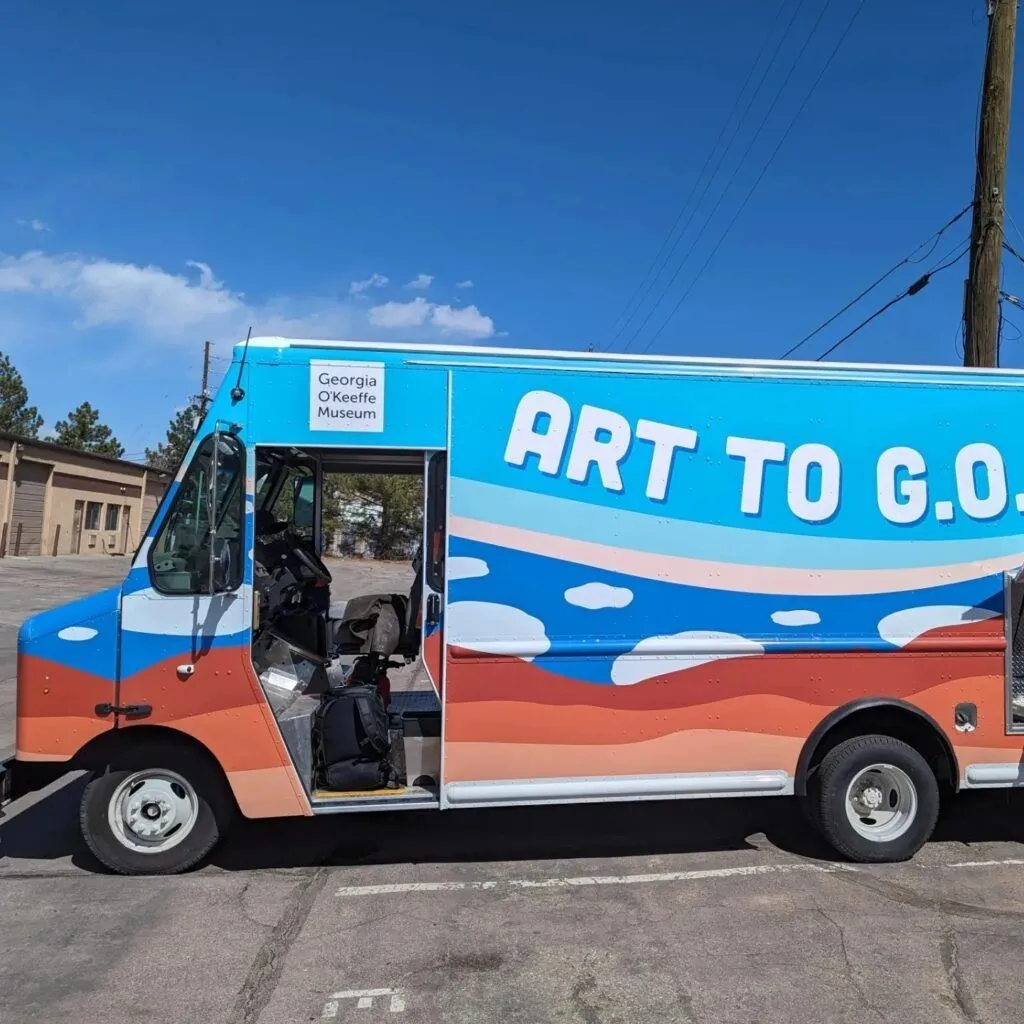 Colorful "Art to Go" truck parked roadside with open side door under a clear blue sky