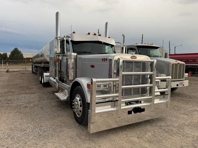 Silver tanker truck with chrome grille parked in a lot under a cloudy sky